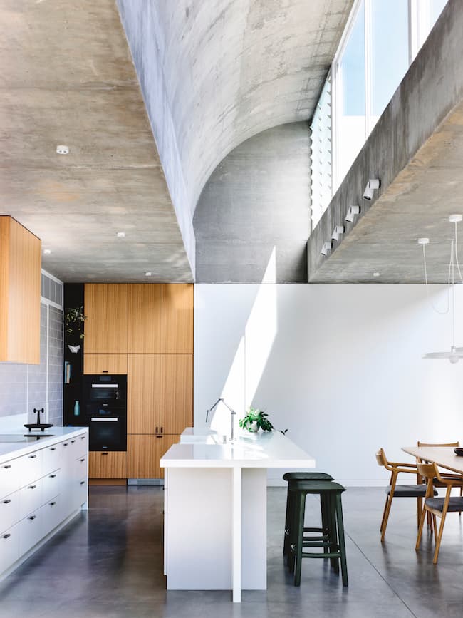 Dramatic kitchen with concrete vaulted ceiling and timber