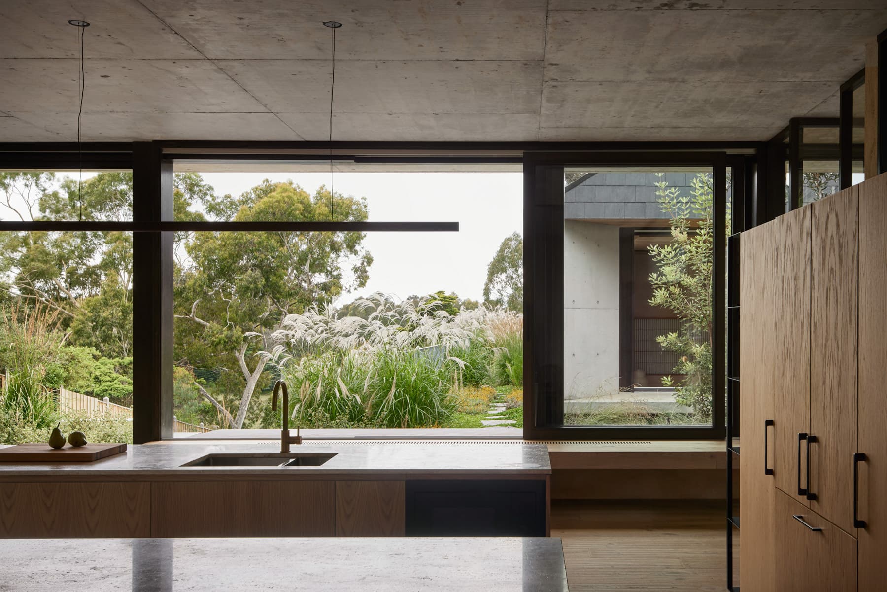 Kitchen with stone benchtop, timber cabinets and garden view
