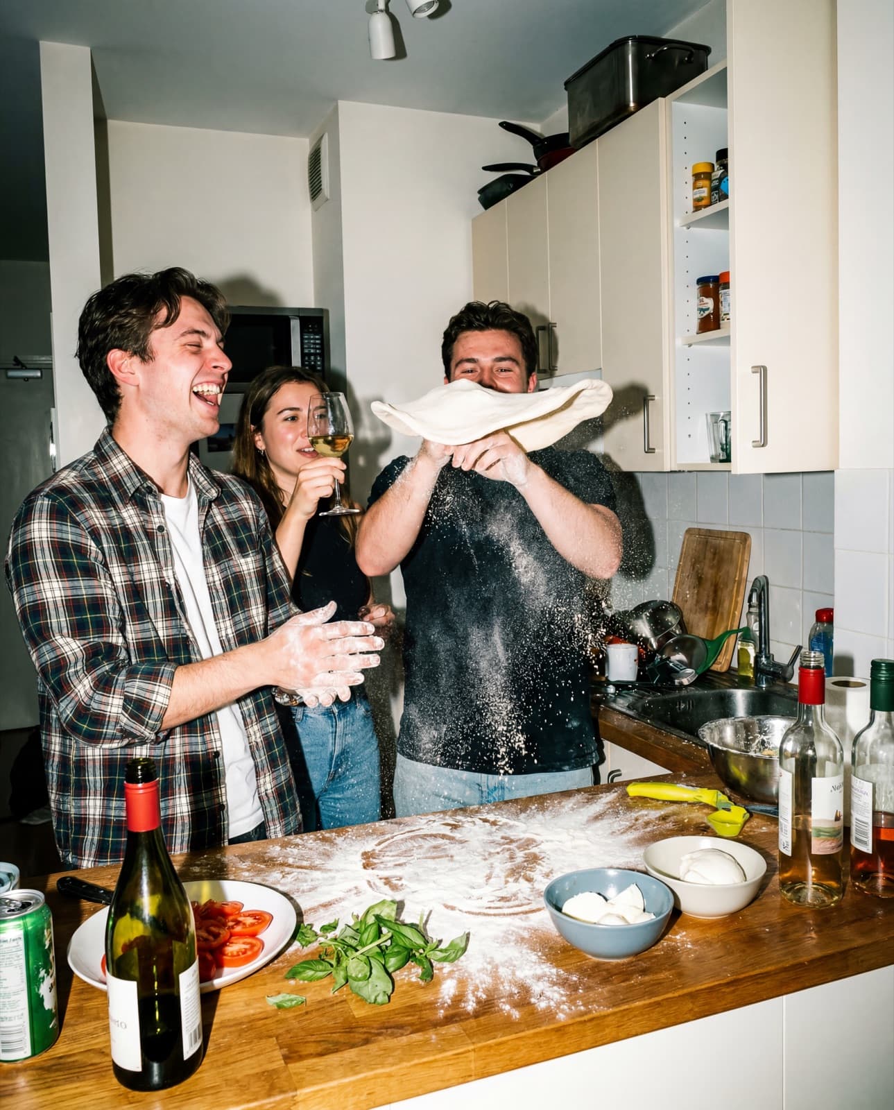 Friends cooking pizza — flour and ingredients everywhere